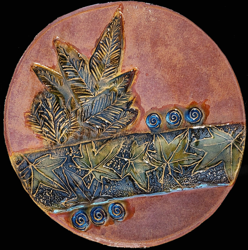 Ceramic plate - Maple and Redwood leaves - on a Sandstone buff clay.  Fired to cone 6, oxidation. Clay has called to Linda Levy for over 50 years.  She has learned wheel throwing techniques, handbuilding, as well as glaze chemistry.  Her latest sculptural works are inspired by working with live models.  Linda's handbuilt plates and platters usually use her hand-created ceramic rollers to impart designs & textures.