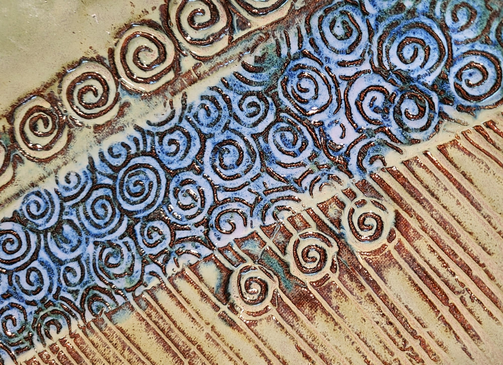 Detail Ceramic plate -Spirals -- on a Sandstone buff clay.  Fired to cone 6, oxidation. Clay has called to Linda Levy for over 50 years.  She has learned wheel throwing techniques, handbuilding, as well as glaze chemistry.  Her latest sculptural works are inspired by working with live models.  Linda's handbuilt plates and platters usually use her hand-created ceramic rollers to impart designs & textures.